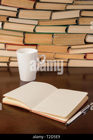 cup, notebook and many books on a wooden table Stock Photo