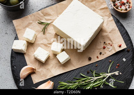 Block of feta cheese, herbs and spicies on black board over concrete background Stock Photo