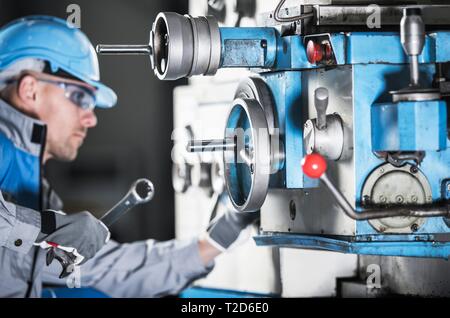 Caucasian Lathe Machine Technician with Wrench Trying To Adjust Machinery Elements. Metalworking Industry Theme. Stock Photo