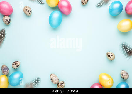 Frame made of colorful Easter eggs on turquoise background. Top view, copy spase, minimal styled. Stock Photo