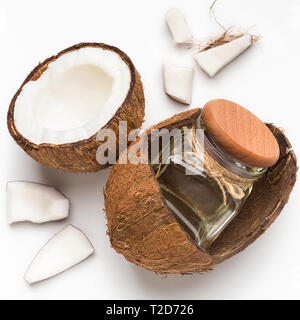 Copped coconut and jar of coconut oil in coco shell on white background, top view. Stock Photo