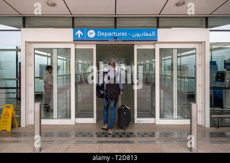 Passenger with a rolling case entering the departures terminal at the Dubai International Airport in United Arab Emirates Stock Photo