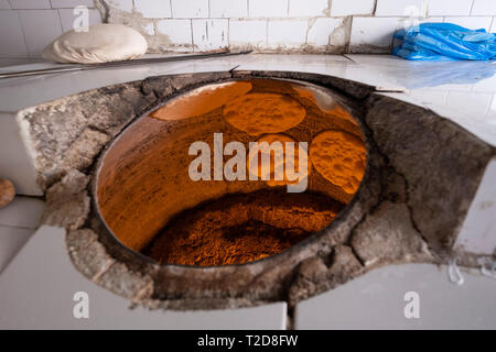 Bread being baked the arabic way on the walls of pita bread tandoor oven Stock Photo