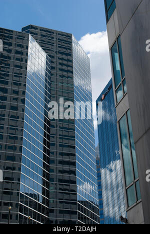 Urban style modern buildings made from glass and steel with reflection of blue sky and clouds on its surface. Stock Photo