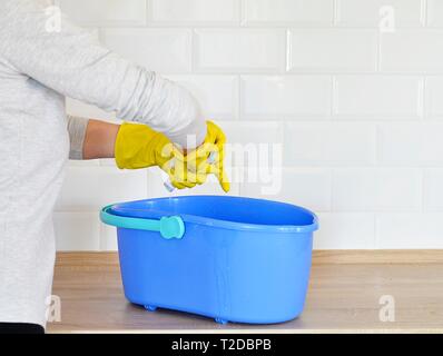 woman washes white tiles on a wooden board has a blue bucket Stock Photo