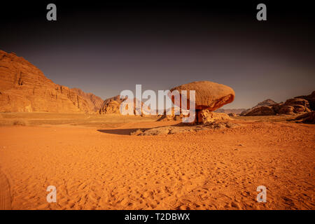Desert of Wadi Rum in Jordan. Impressive landscape with a mushroom-shaped rock formation in the foreground surrounded by rocky mountains. Presence of  Stock Photo