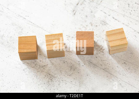 Four blank wooden cubes on white cement board. Stock Photo