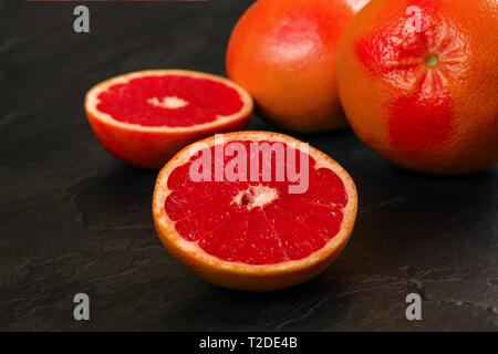Detail of red grapefruit one citrus halved, on black slate like board. Stock Photo