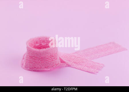 Lace ribbon neatly twisted into a ring on a pink background. Romantic background. Stock Photo