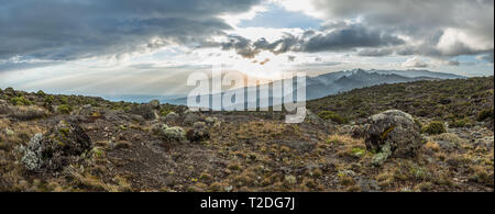 Panoramic view of sunset over Mount Meru in Tanzania taken from the Shira Cave camp on Kilimanjaro. Sunrays burst through the dramatic clouds. Stock Photo