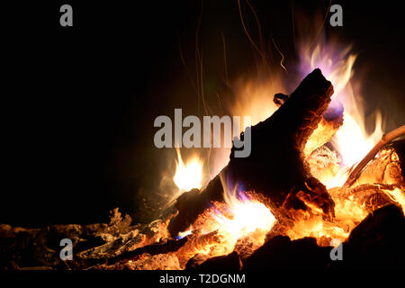 A campfire burns brightly in an outdoor, stone fire pit on a cold early spring night. Stock Photo