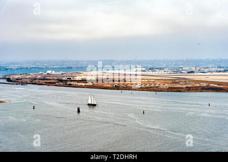 View of Coronado Island from Point Loma. Ocean with a sailboat in harbor channel under cloudy skies. Stock Photo