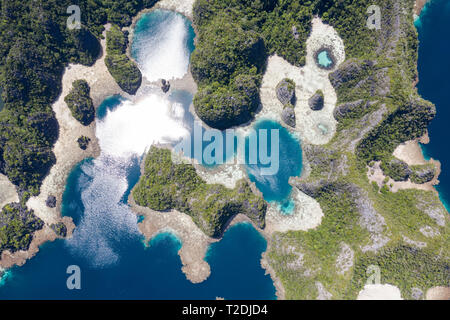 A bird's eye view shows healthy reefs surrounding remote limestone islands in Raja Ampat. This area is known for its incredible marine biodiversity. Stock Photo