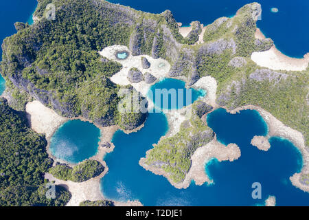 A bird's eye view shows healthy reefs surrounding remote limestone islands in Raja Ampat. This area is known for its incredible marine biodiversity. Stock Photo