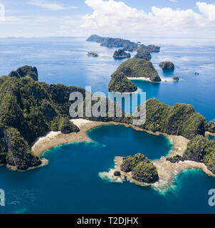 A bird's eye view shows healthy reefs surrounding remote limestone islands in Raja Ampat. This area is known for its incredible marine biodiversity. Stock Photo