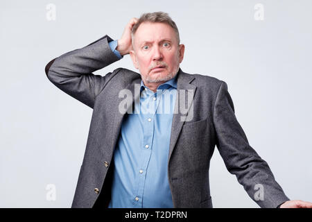 Pensive senior man in suit scratching his head. Being confused and upset by his finance. Stock Photo