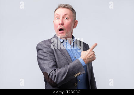 Surprised handsome senior man in suit with pointing with finger. Copyspace Stock Photo