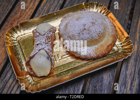 A typical Sicilian cannoli and a Genovese pastry on a wooden table. Food concept. Landscape format. Stock Photo