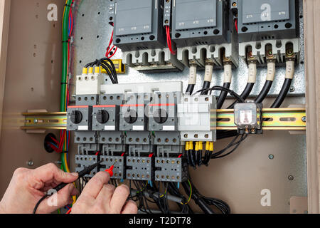 Chiller engineer testing a wiring circuit in a control panel Stock Photo