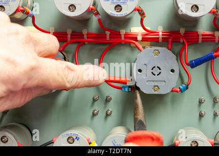 Electrician using long nose pliers and screwdriver to connect wiring to a panel switch Stock Photo