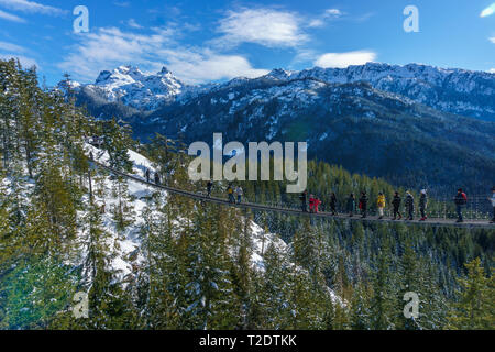 People walking across the Suspension Bridge on top of a mountain, Squamish, BC, Canada. Stock Photo