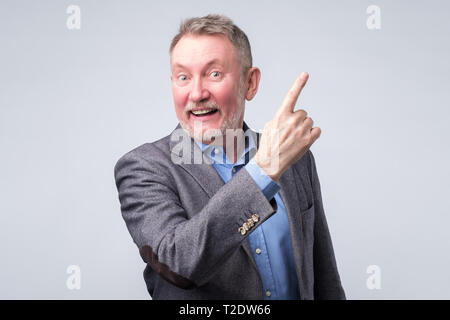 Happy handsome senior man in suit with pointing with finger. Copyspace Stock Photo
