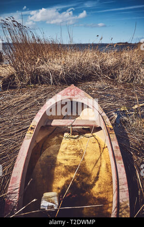 Retro toned picture of a sunken small fishing rowboat in the reeds. Stock Photo