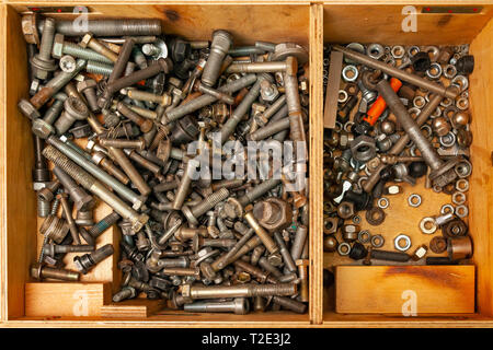 Wooden box with a bunch of nuts, bolts and screws. Tools and fasteners in the workshop. Stock Photo