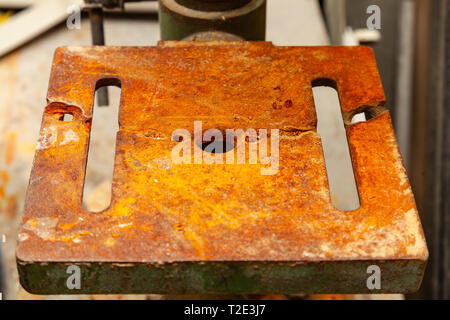 An iron plate with holes covered with a thick layer of rust that eats away metal Stock Photo