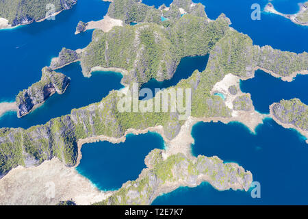 A bird's eye view shows healthy reefs surrounding remote limestone islands in Raja Ampat. This area is known for its incredible marine biodiversity. Stock Photo