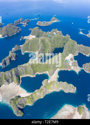 A bird's eye view shows healthy reefs surrounding remote limestone islands in Raja Ampat. This area is known for its incredible marine biodiversity. Stock Photo