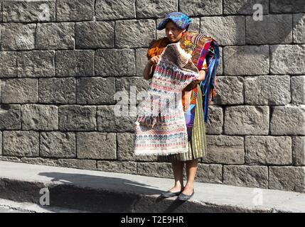 Isolated Guatemala Woman standing on Street Corner on Chichicastenango Market Day and selling Traditional Artisan Handicraft Textile and Carpets