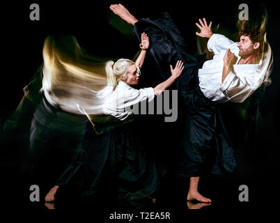 two budokas fighters man and woman practicing Aikido studio shot isolated on black background Stock Photo