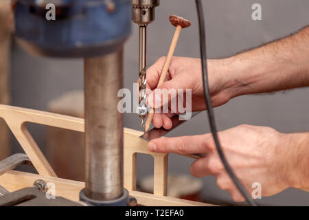 Close up of experienced carpenter in work clothes and small buiness owner measures a wooden board with a marks with pencil the necessary points for sl Stock Photo