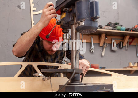 Home repair concepts, close up. Handicraft Carpentry. Cabinet-maker hands drilling a wooden plank using electric drill on the working table in the wor Stock Photo