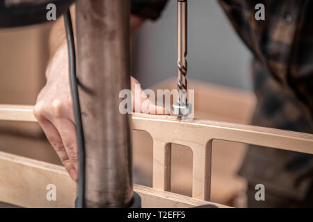 Home repair concepts, close up. Handicraft Carpentry. Cabinet-maker hands drilling a wooden plank using electric drill on the working table in the wor Stock Photo