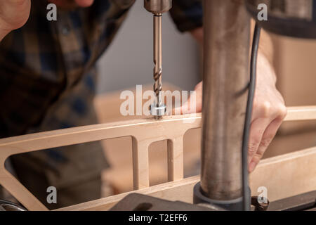 Home repair concepts, close up. Handicraft Carpentry. Cabinet-maker hands drilling a wooden plank using electric drill on the working table in the wor Stock Photo