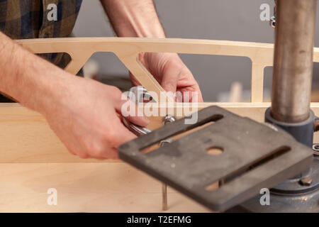 Home repair concepts, close up. Handicraft Carpentry. Cabinet-maker hands tightens the nuts  on wooden board with a clamp on the working table in the  Stock Photo