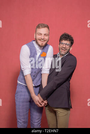 gay men acting silly, acting lovely and cute holding hands together while excited. photo-shoot in studio. Stock Photo