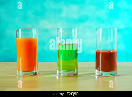 Fresh orange, apple and tomato juices in glasses in bright table setting. Stock Photo