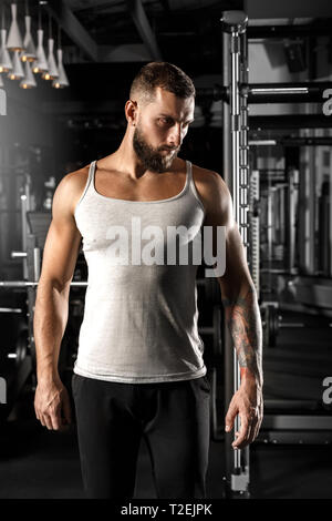 Bearded man bodybuilder standing at gym looking aside thoughtful Stock Photo
