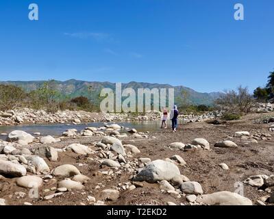 Two girls, sisters, playing along the banks of the Ojai River, on a fine spring day with mountains and lush vegetation, Ojai, California, USA Stock Photo