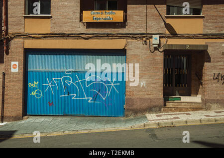Close-up of blue garage gate and door on a brick building in a street of Caceres. A charming town with a fully preserved old city center in Spain. Stock Photo