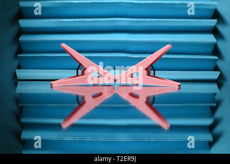 Two pink clothes pegs on blue background. Stock Photo