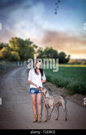 Young woman with large, grey Weimaraner/ghost dog in the country Stock Photo