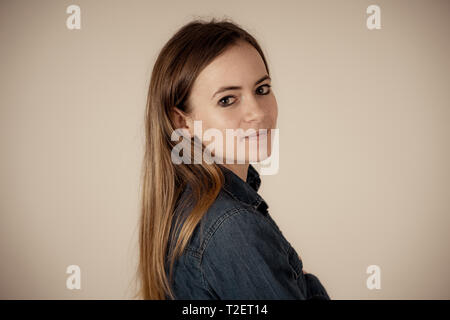 Studio portrait of young beautiful teenager woman with blond hair wearing jean shirt feeling confident, relaxed posing and modeling. Isolated on neutr Stock Photo