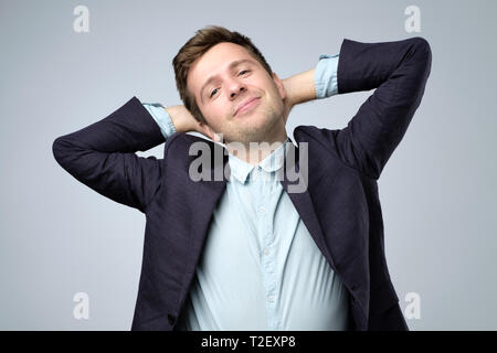 Pensive young man in suit planning vacation. Dreamy office manager resting at work. Stock Photo
