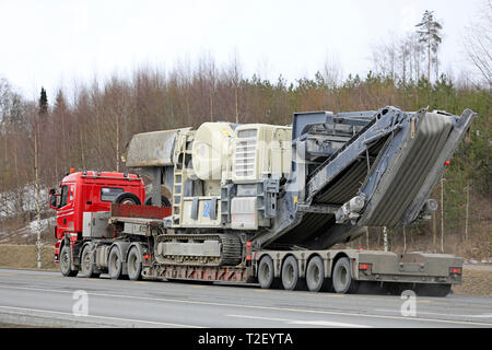 Forssa, Finland - March 30, 2019: Scania R620 truck of Veljekset Makitalo Oy hauls Metso Lokotrack crusher on low loader trailer along road, rear view Stock Photo