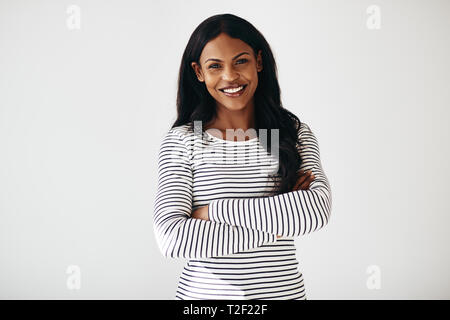 Young African American female entrepreneur smiling while standing with her arms crossed against a white background Stock Photo