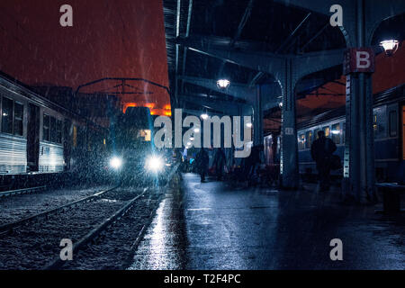 Human silhouettes unrecognizable in the dark on a train station on the platform during a snow storm and a train in the station on tracks in Bucharest  Stock Photo